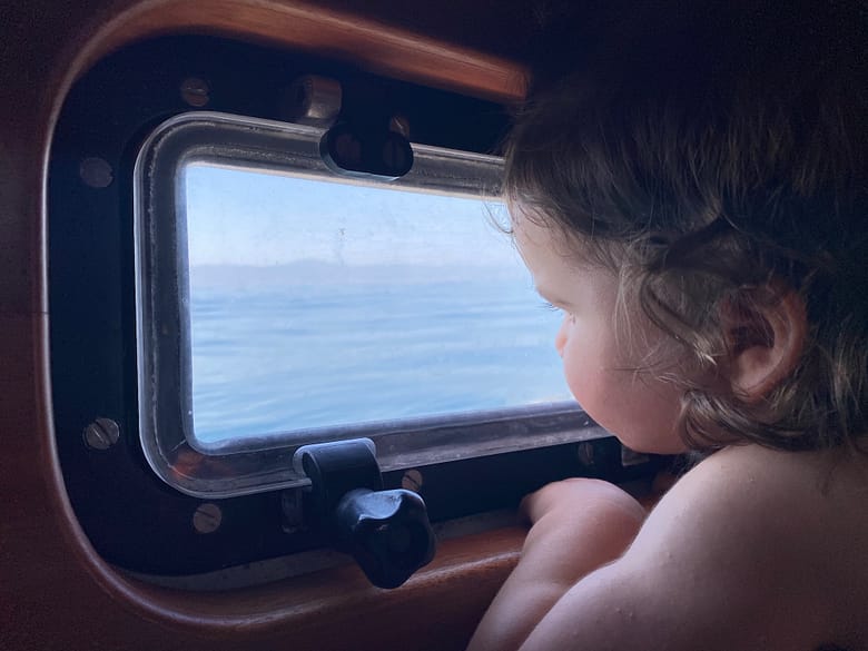 Toddler looking out the window of a sailing boat while travelling Toddler looking out the window of a sailing boat while travelling
